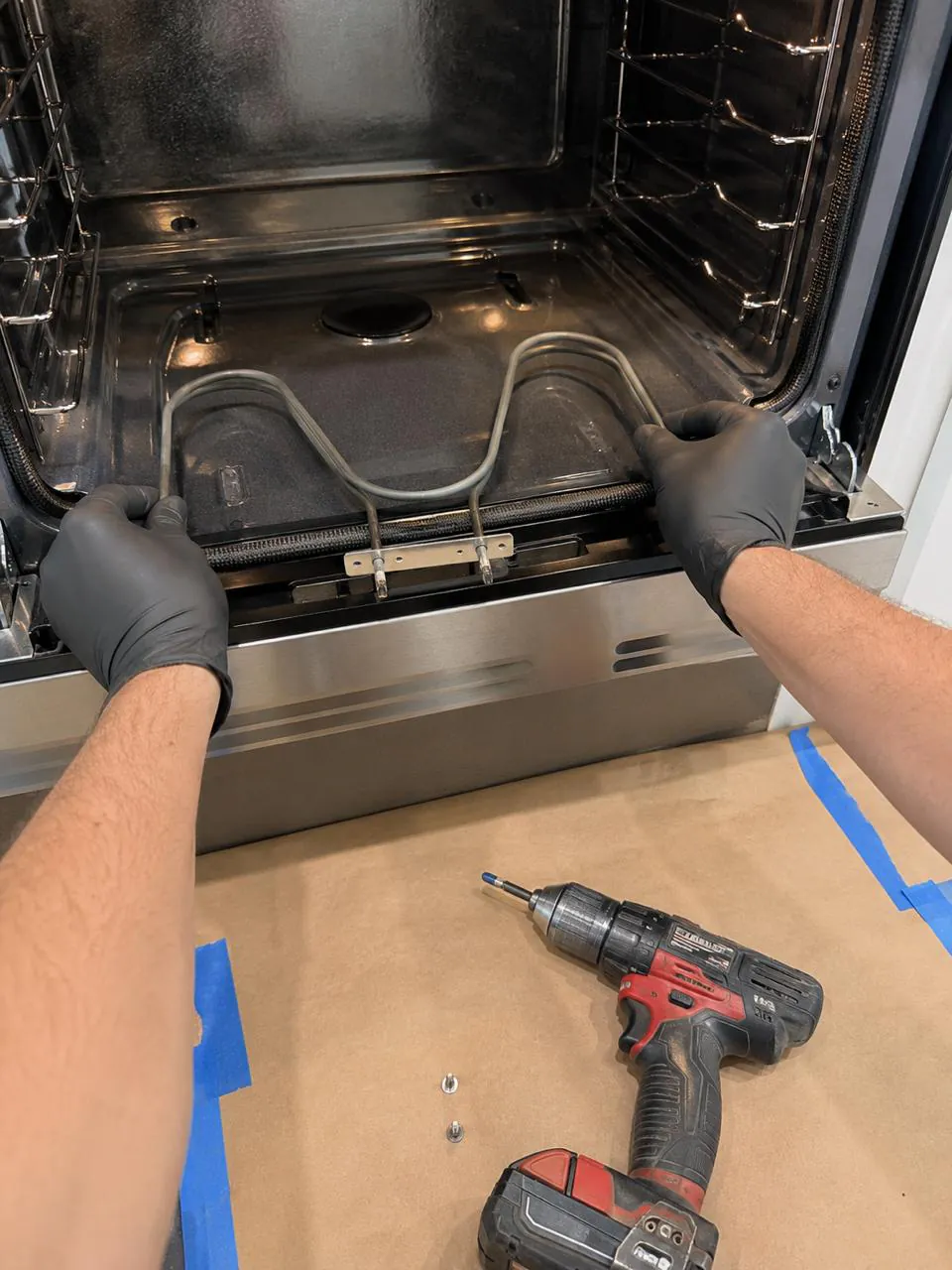 Technician replacing bake heating element inside oven in San Diego home