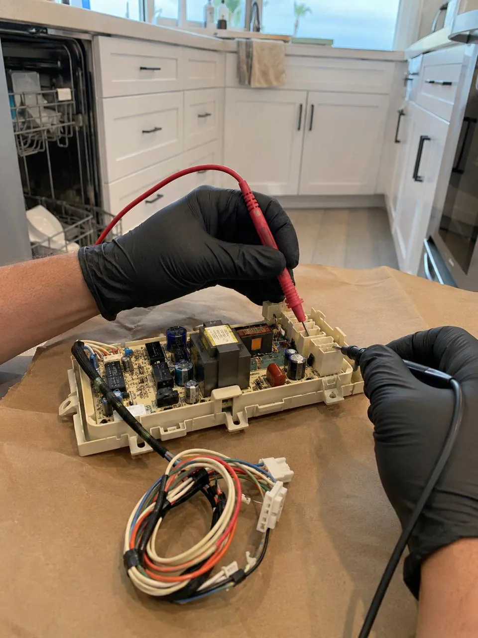 Technician testing dishwasher control board with multimeter in San Diego kitchen