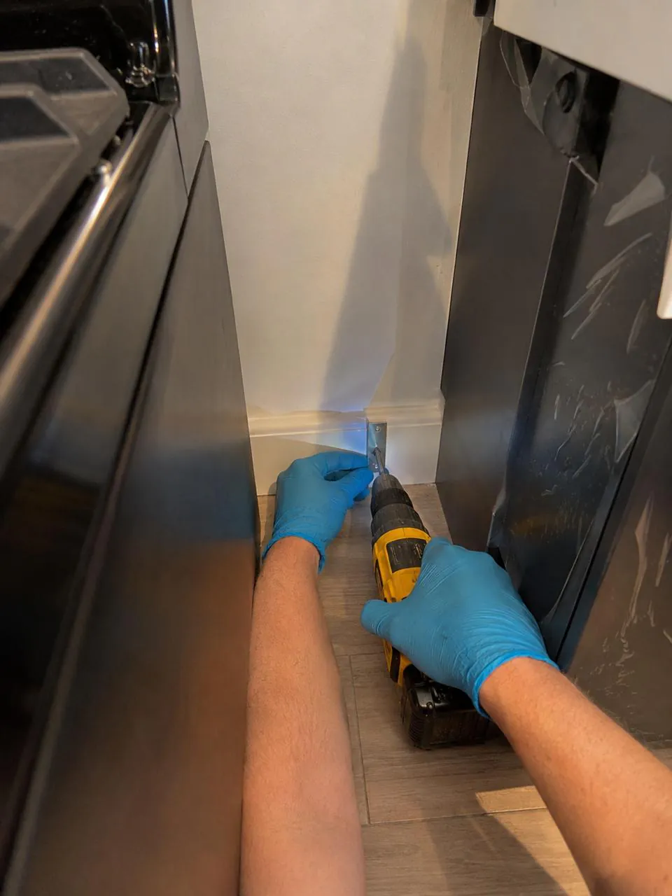 Securing anti-tip bracket behind a range with a cordless drill