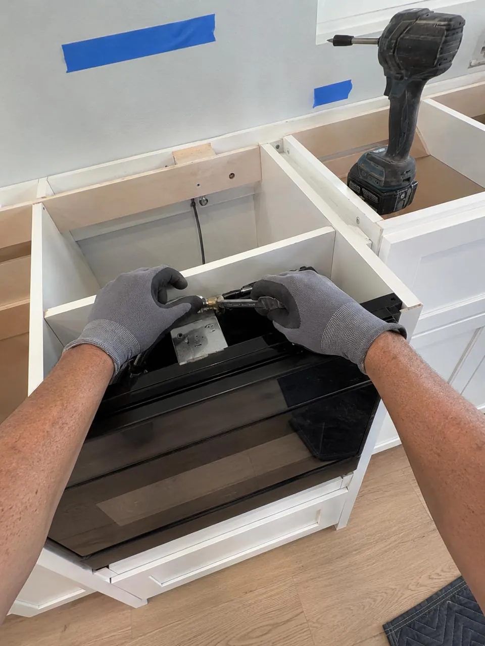 Technician servicing drop-in cooktop in a kitchen island cabinet