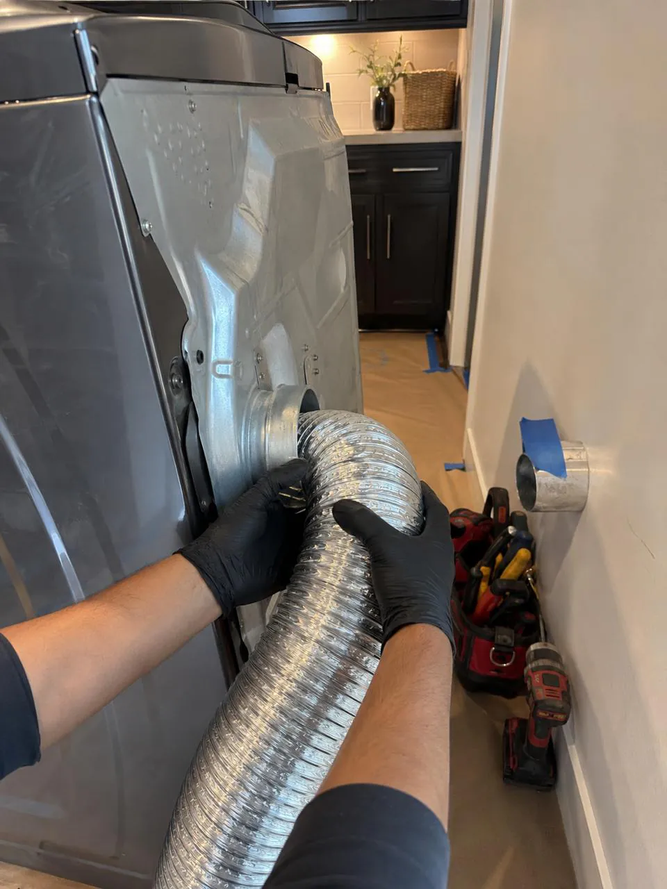 Technician connecting dryer vent hose in San Diego laundry room