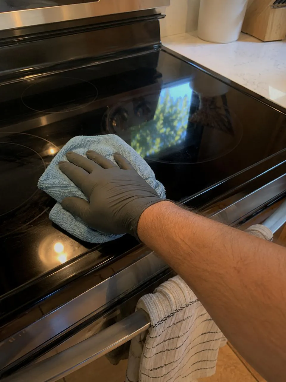 Technician cleaning glass electric range cooktop in San Diego kitchen