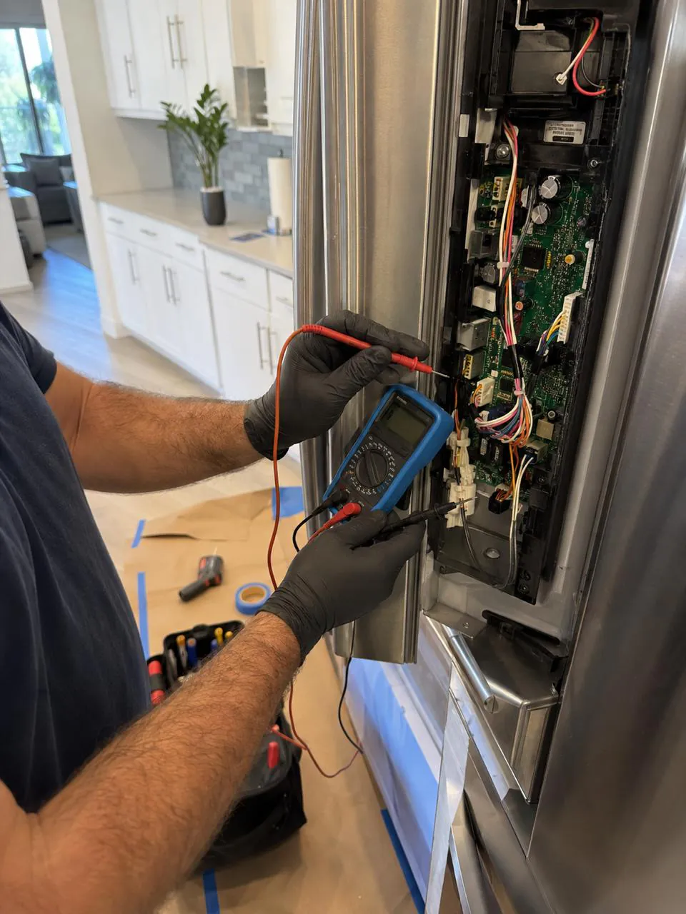 Technician testing refrigerator control board with multimeter in San Diego home