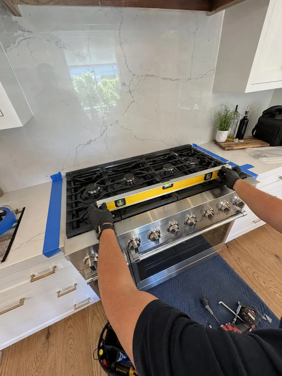 Technician leveling a stainless gas range in a San Diego kitchen