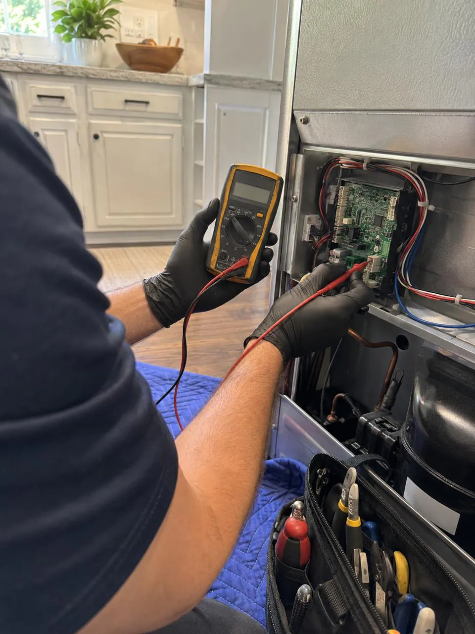 Technician testing refrigerator control board with multimeter in San Diego home