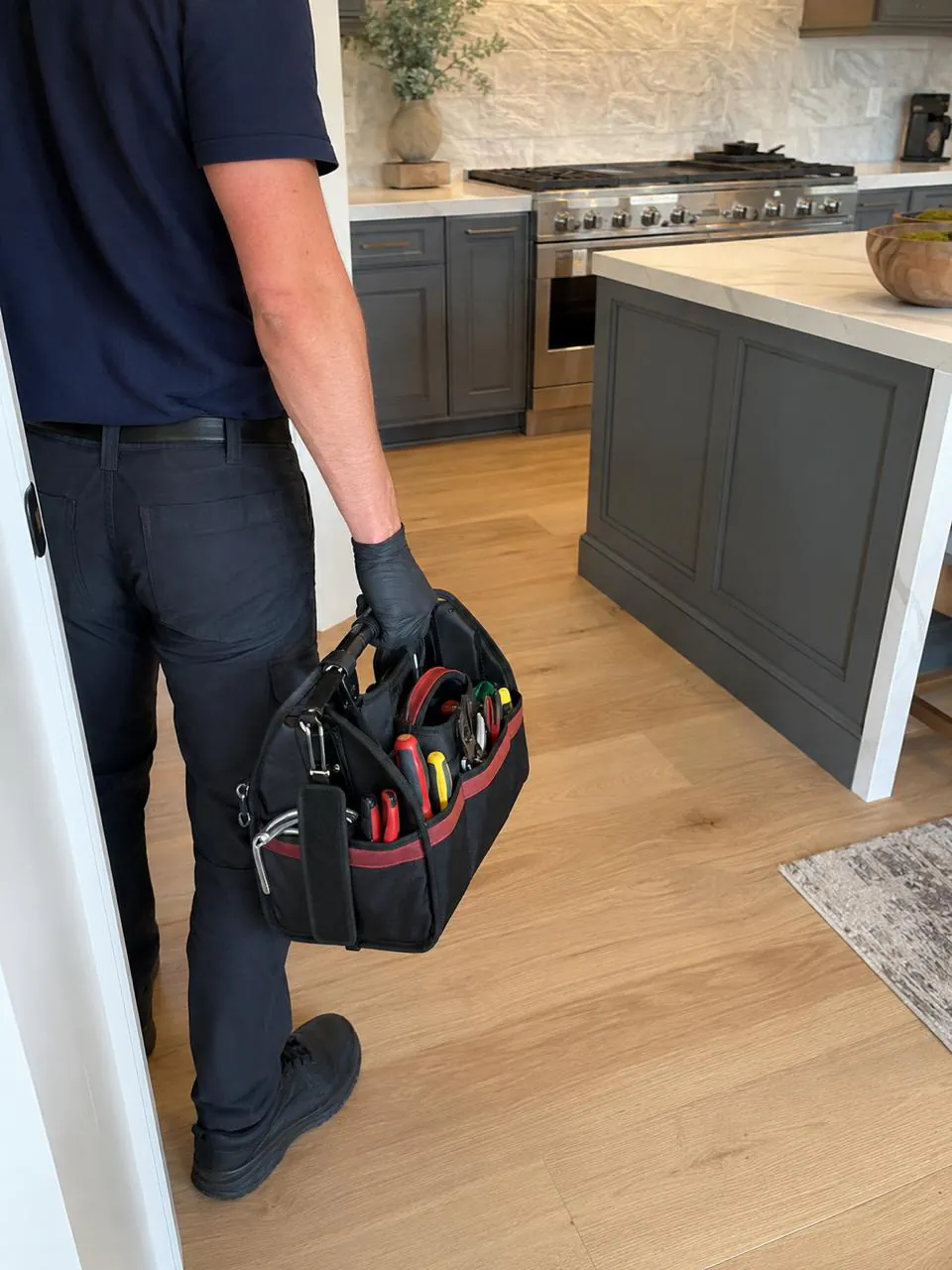 Appliance technician with a tool bag in a San Diego home kitchen